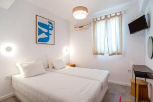 a bedroom with two white beds and a television at Adelfia Studios in Parikia