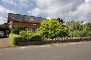 a house on the side of a road with bushes and trees at Ferienwohnung Thomée in Looft