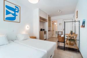 a bedroom with a white bed and a table at Adelfia Studios in Parikia