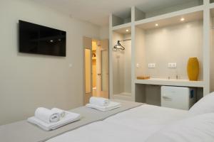 a white bedroom with a bed with two towels at Artemida Beach House in Artemida +128 photos