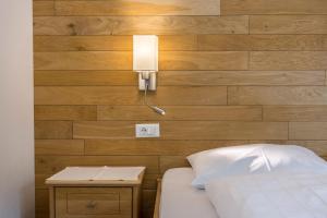 a bedroom with a bed and a lamp on a wall at Garni Hotel Gardena App Dolomites 3 in Santa Cristina Gherdëina