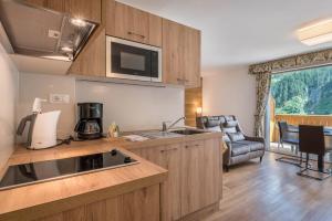 a kitchen with a sink and a living room at Garni Hotel Gardena App Dolomites 3 in Santa Cristina Gherdëina