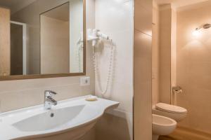 a bathroom with a sink and a toilet and a mirror at Garni Hotel Gardena App Dolomites 3 in Santa Cristina Gherdëina +18 photos