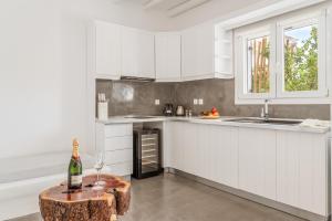 a kitchen with white cabinets and a table with a bottle of wine at Ow Andros Suite 3,Private Whirlpool in Andros