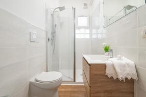 a white bathroom with a toilet and a shower at Sa Babbajola in Cagliari +16 photos