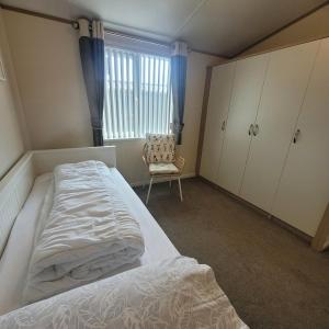 a bedroom with a bed and a chair and a window at Trevella Lakeview Lodge in Newquay