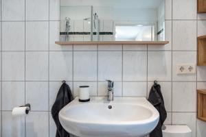 a white bathroom with a sink and a mirror at tierfreundliche Ferienwohnung in Adamshoffnung +10 photos