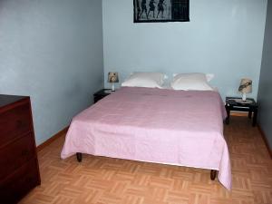 a bedroom with a bed with a pink bedspread and two tables at Le Paillassou in Blanzac