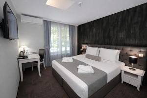 a hotel room with a large bed and a desk at Hotel Alexandar II in Skopje