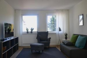 a living room with a couch and a chair and two windows at Ferienwohnung An Der Dorfkirche in Vipperow