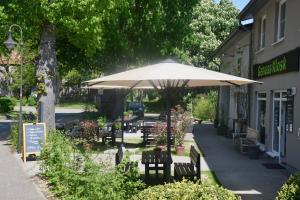 a table and chairs under an umbrella in front of a building at Ferienwohnung An Der Dorfkirche in Vipperow +9 photos