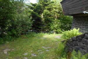 a grassy yard next to a house with trees at Chalet les Sonnailles in Mont-Dore