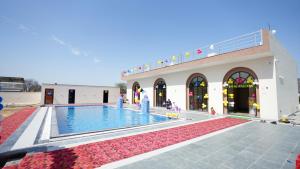a building with a swimming pool in front of a building at iv hotel Ajmer in Madār