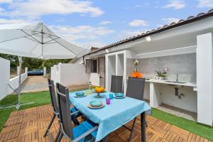 eine Terrasse mit einem blauen Tisch, Stühlen und einem Sonnenschirm in der Unterkunft Ikigai in Buggerru