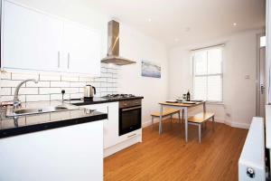 a white kitchen with a sink and a table at 21 Gyllyng Street in Falmouth