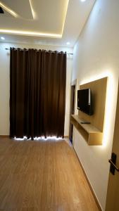 a living room with a tv and a brown curtain at iv hotel Ajmer in Madār