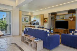 a living room with blue couches and a tv at Artemida Beach House in Artemida