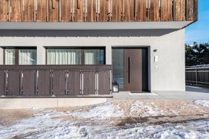 a house with brown doors and a snowy driveway at Mountain Meadows Apt 1 in Valdaora