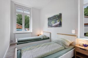 a bedroom with two beds and two windows at Reit- und Ferienhof Alte Dorfschule in Holstenniendorf