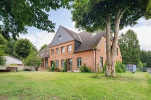 a large brick house with a tree in the yard at Reit- und Ferienhof Alte Dorfschule in Holstenniendorf