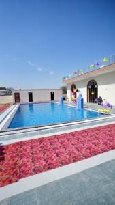 a large swimming pool with red flowers in a building at iv hotel Ajmer in Madār +26 photos