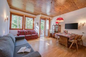 a living room with a couch and a table and a tv at Il nido nella Pineta Central in Ski resort - Happy Rentals in Bardonecchia