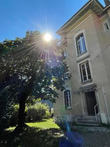 a tree in front of a house with the sun at Villa Isabelle in Allevard +9 photos