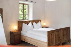 a bedroom with a large white bed with two lamps at Ansitz Baumannhof Apt Gotik in Falzes