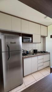a kitchen with a stainless steel refrigerator and white cabinets at Flat 707 Moderno e Espaçoso, próximo ao Praia Clube in Uberlândia