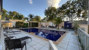 a swimming pool with tables and chairs on a patio at Flat 707 Moderno e Espaçoso, próximo ao Praia Clube in Uberlândia
