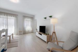 a white living room with a tv and a couch at Refúgio Estrela do Mar in Quarteira