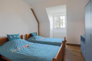two beds in a bedroom with blue sheets at Les Camelias in Locquirec