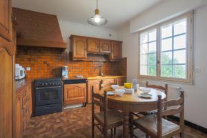 a kitchen with a wooden table with chairs and a dining room at Les Camelias in Locquirec