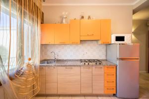 a kitchen with yellow cabinets and a stainless steel refrigerator at Appartamento Croce del Sud 8 in Bibione