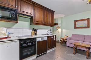 a kitchen with wooden cabinets and a living room at Puente del Narcea 4 in Cibuyo