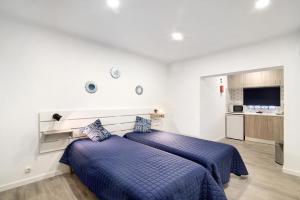 two beds in a white room with blue sheets at Apartamento nº4 - Beach in Moncarapacho
