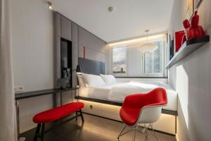 a bedroom with a bed and a red chair at citizenM Paris Gare de Lyon in Paris