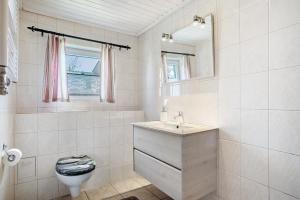 a white bathroom with a toilet and a sink at Ferienhaus Struve in Trent +13 photos