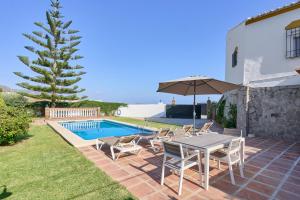 a patio with a table and chairs next to a swimming pool at Villa El Peli in Nerja