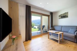 a living room with a couch and a large window at Teutenhofer Kastanie in Feldthurns