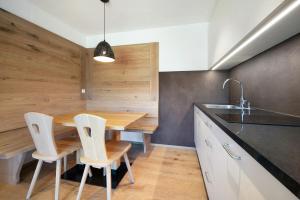 a kitchen with a wooden table and white chairs at Teutenhofer Kastanie in Feldthurns