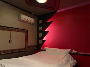 a bedroom with a white bed with a red wall at 福井ホテルシルビア in Fukui