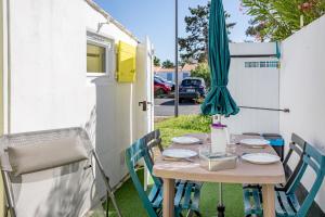 a table with a umbrella and plates on it at Studio piscine partagée in Bretignolles-sur-Mer
