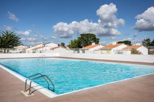 a swimming pool with blue water and houses at Studio piscine partagée in Bretignolles-sur-Mer