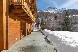 a snow covered sidewalk next to a building with a mountain at Chalet de La Poya in Valtournenche