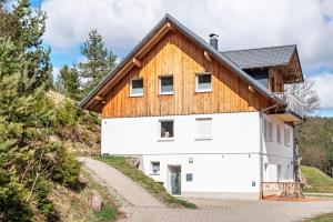 ein weißes Haus mit einem Holzdach auf einem Hügel in der Unterkunft Rudemsmännchen in Eisenbach