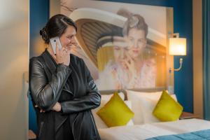 a woman talking on a cell phone in a hotel room at Mercure Berlin Wittenbergplatz in Berlin