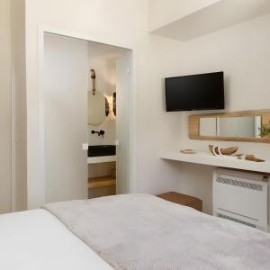 a white bedroom with a bed and a flat screen tv at Batsi view house in Andros