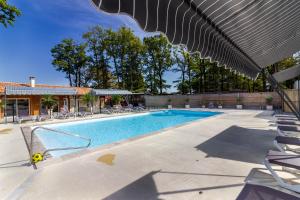 a swimming pool with chairs and an umbrella at Gite 4 de l'Orée du Bois in Thenon