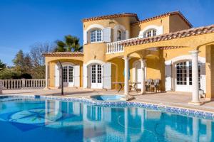 a large house with a swimming pool in front of it at Madrague St Vincent Apt B in Le Grau-dʼAgde
